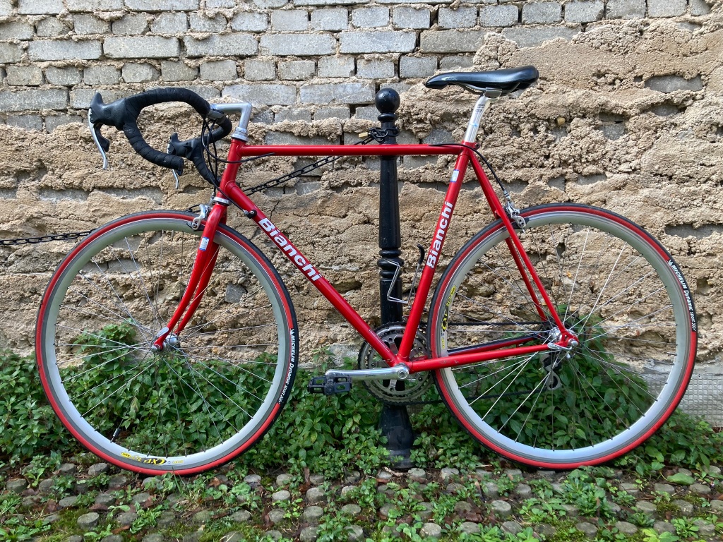 Vélo de course Bianchi de couleur rouge le long d'un mur. Le vélo a été tourné dans l'autre sens.